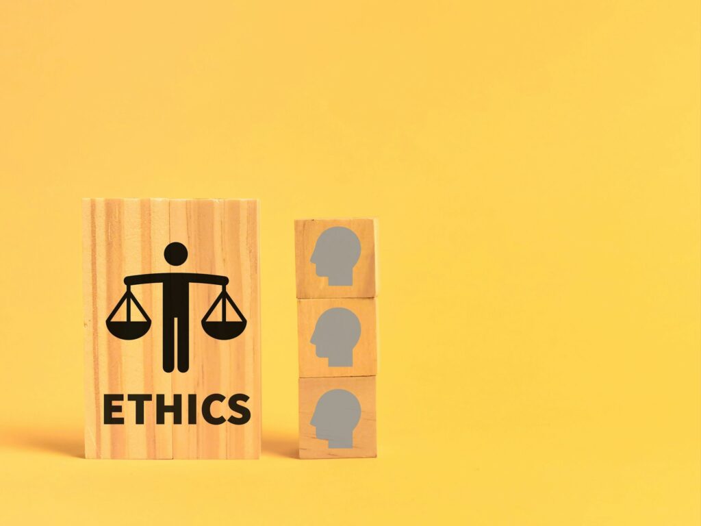 Wooden block with an illustration of a person with a scale and the word ethics on yellow background