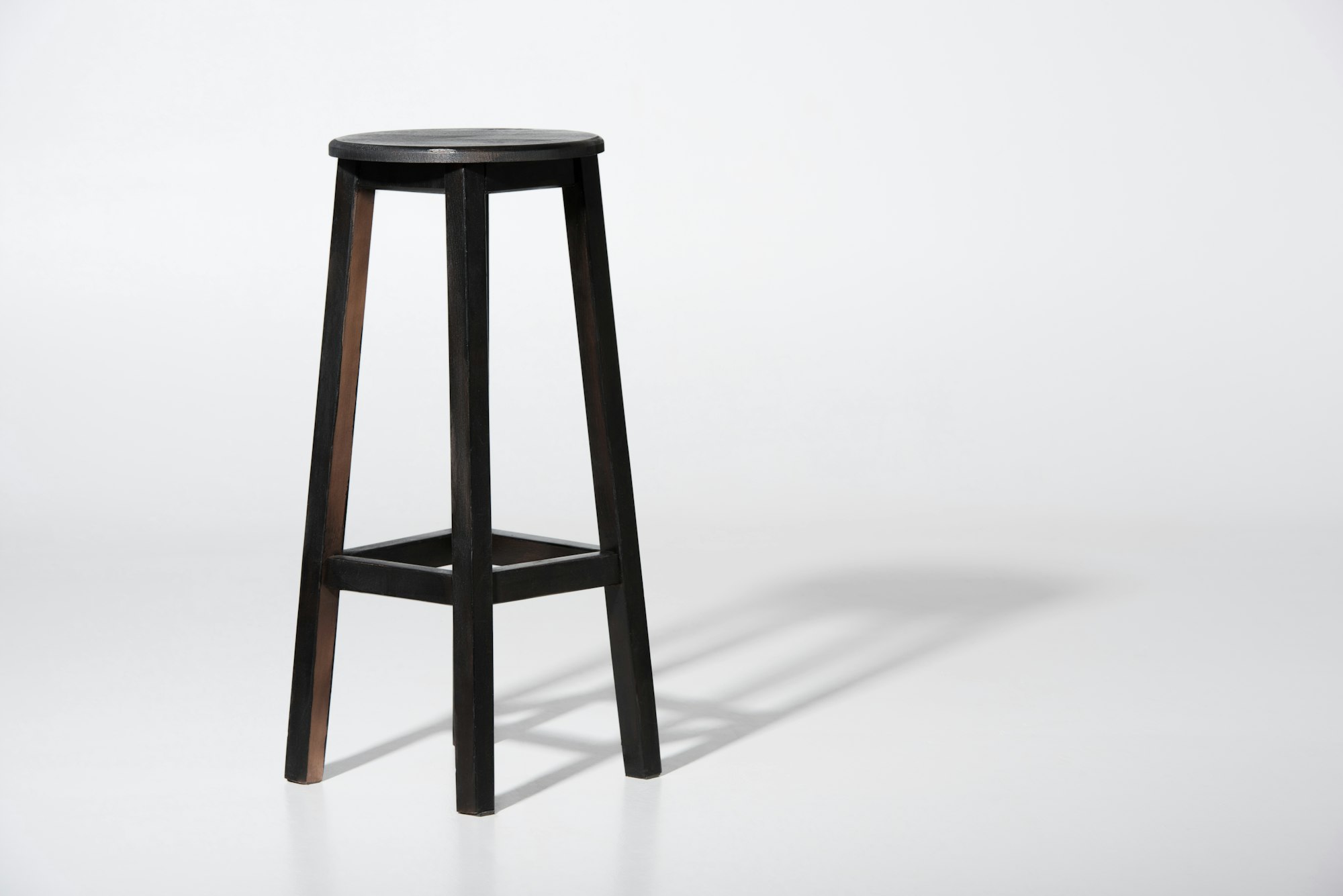 Studio shot of classic black tall wooden barstool standing on white