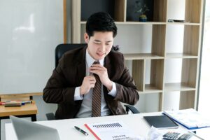 Asian young businessman tying necktie in the office.