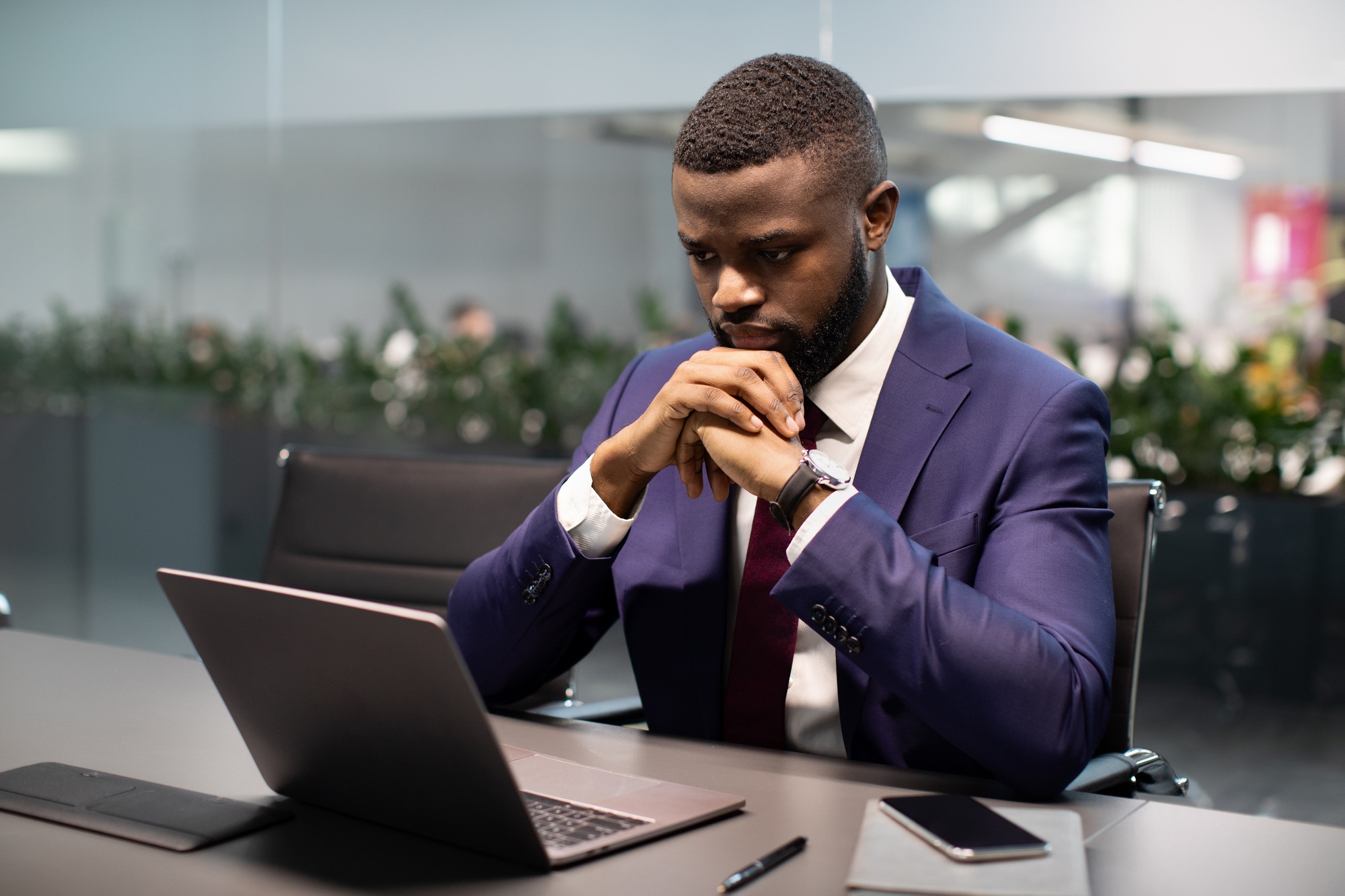 Pensive african american young entrepreneur working on laptop