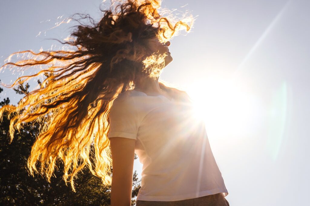 Happy girl with long hair in sunshine.